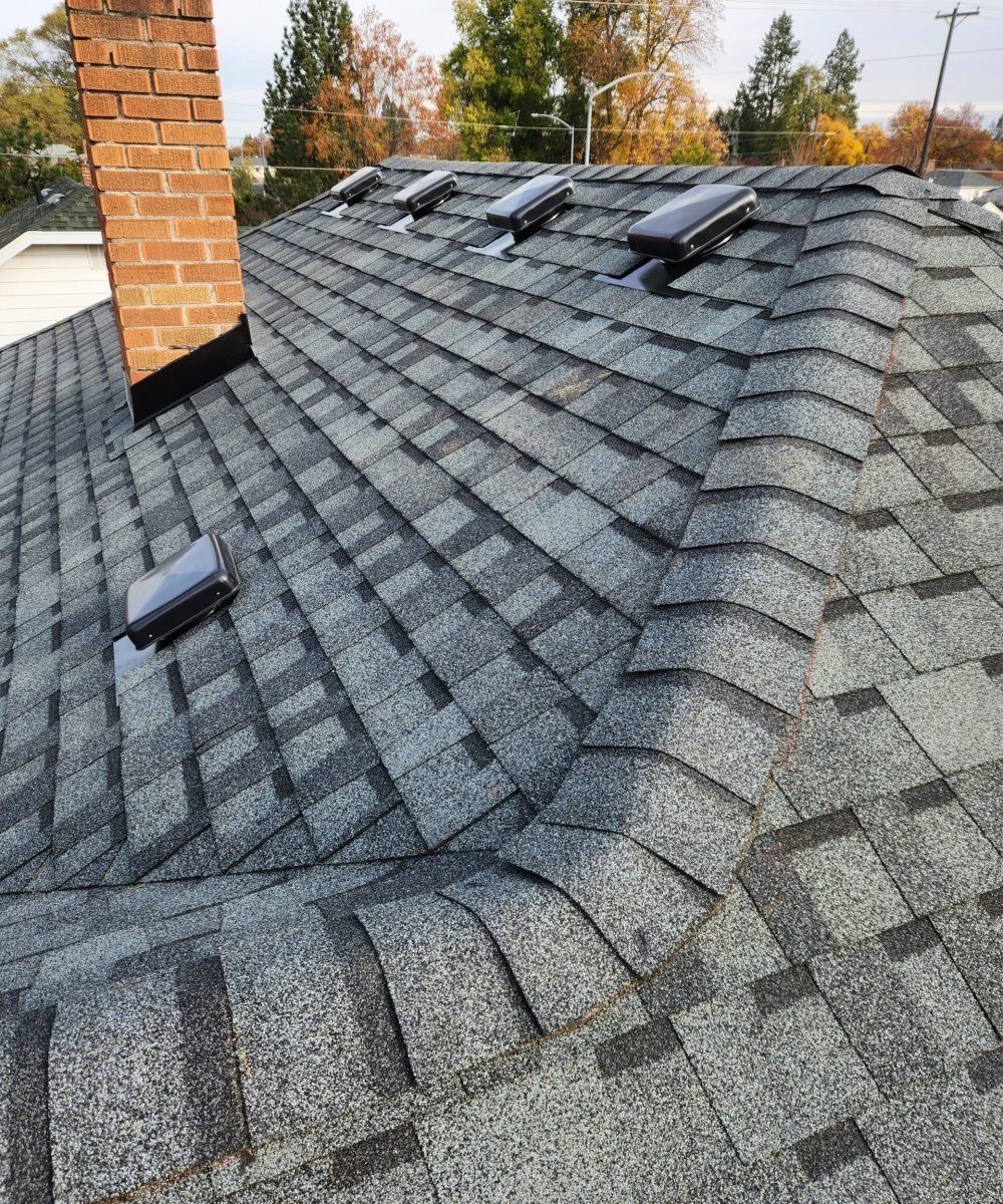 Close-up of chimney flashing, roof ridge shingles, and vent installation completed by RC Roofing
